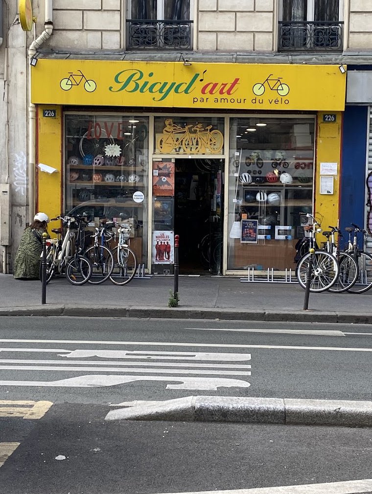 La devanture jaune de Bicycl'Art au 226 rue La Fayette, avec l'enseigne « par amour du vélo » et des vélos garés devant la vitrine.